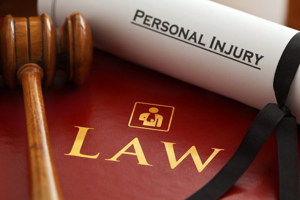 Scroll reading personal injury and gavel on top of book with word Law on the front