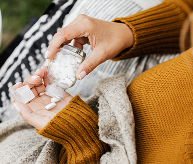 woman putting pills into her hand from a bottle