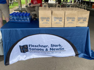 A Table, covered with a blue and white FSTN tablecloth, has goodie bags and water bottles on it for the participants of the walk.