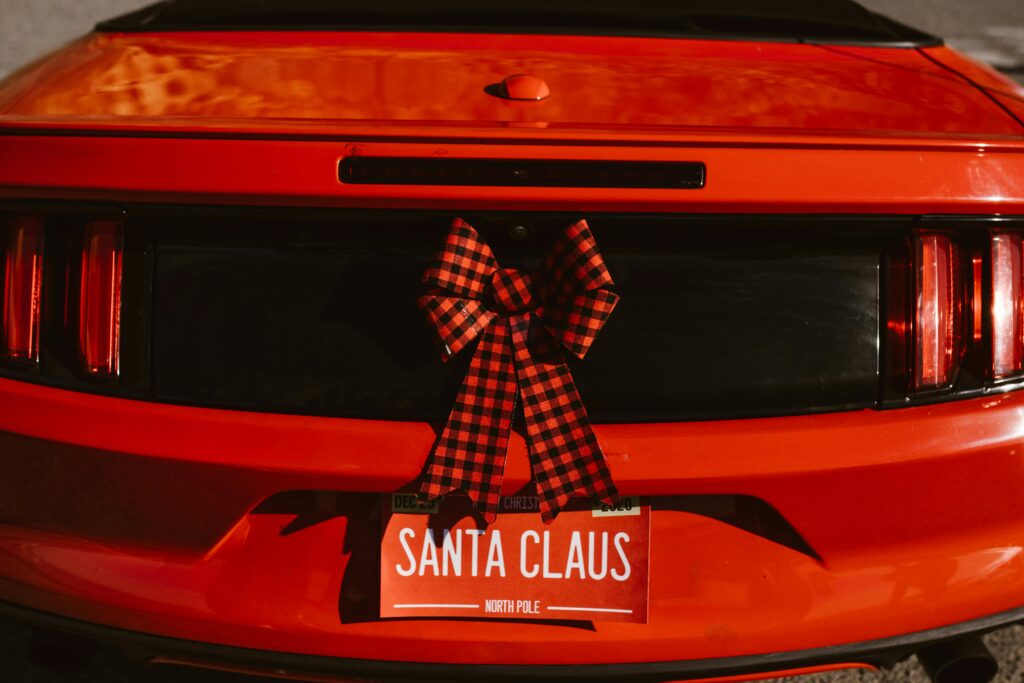 Red car with a bow on it and a license plate that says SANTA CLAUS