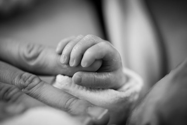 a newborn's hand holding an adult's finger