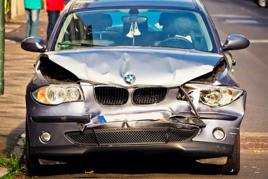 Silver car with crumpled front bumper and hood from car accident